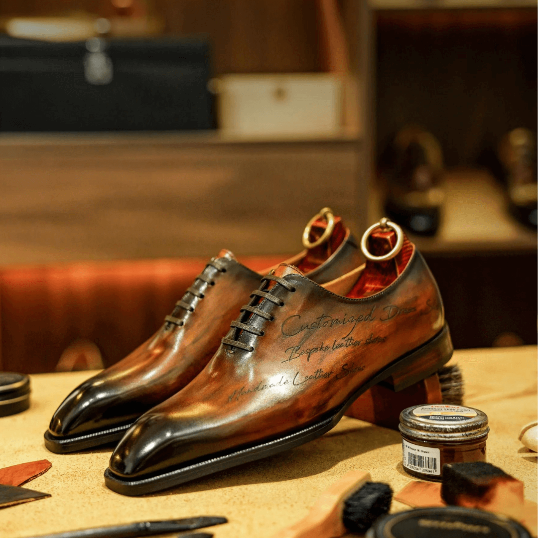 Elegant pair of handcrafted chestnut brown patina oxford shoes displayed on a wooden surface in a luxurious setting, surrounded by shoe care tools and accessories.