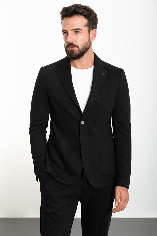 Man wearing a black casual summer suit, blending modern style with comfort for warm-weather occasions.